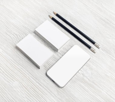 Akıllı telefon, boş kartvizitler ve tahta arka planda kalemler. Marka kırtasiye şablonu. Marka kimliği için model.