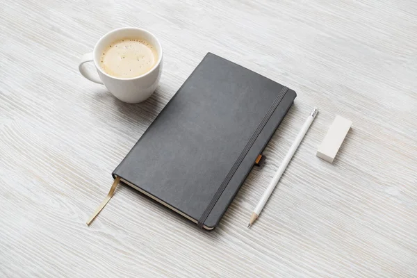 空白闭式笔记本 橡皮和咖啡杯的照片 背景为轻型木制 反应灵敏的设计模型 文具元素 放置设计的模板 — 图库照片