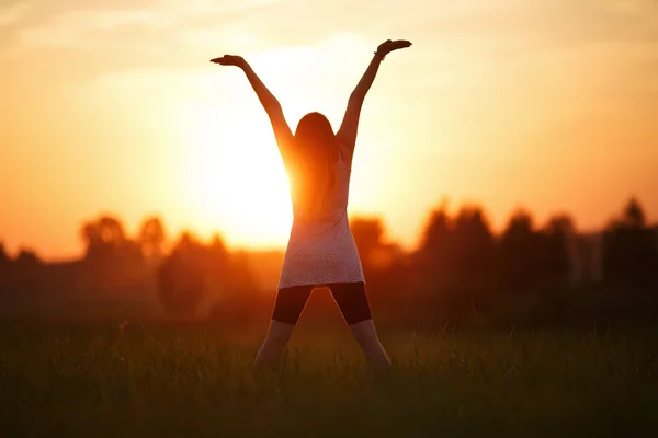 Chica con las manos arriba en el fondo del atardecer — Foto de Stock