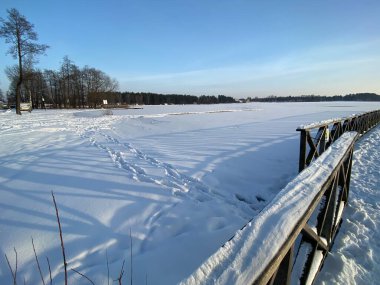 Wodawa yakınlarındaki donmuş Biae Gölü manzarası. Güneş batmadan önce turuncu güneşin yoğun kar manzarası. Altın saat. 