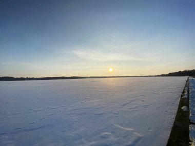 Wodawa yakınlarındaki donmuş Biae Gölü manzarası. Güneş batmadan önce turuncu güneşin yoğun kar manzarası. Altın saat. 