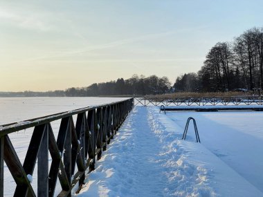 Wodawa yakınlarındaki donmuş Biae Gölü manzarası. Güneş batmadan önce turuncu güneşin yoğun kar manzarası. Altın saat. 
