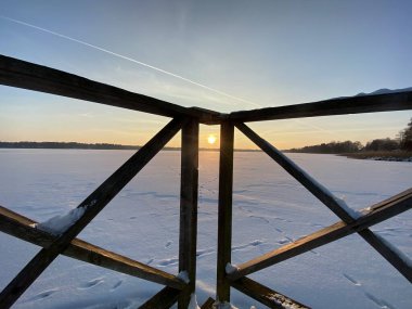 Wodawa yakınlarındaki donmuş Biae Gölü manzarası. Güneş batmadan önce turuncu güneşin yoğun kar manzarası. Altın saat. 