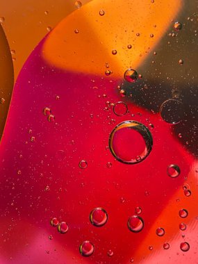 yüzen yağ damlaları farklı renklerde parıldıyor ve renkli bir arkaplanda hava kabarcıklarının yanında şekilleniyor.