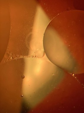 yüzen yağ damlaları farklı renklerde parıldıyor ve renkli bir arkaplanda hava kabarcıklarının yanında şekilleniyor.