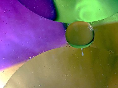 yüzen yağ damlaları farklı renklerde parıldıyor ve renkli bir arkaplanda hava kabarcıklarının yanında şekilleniyor.