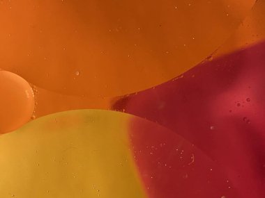 yüzen yağ damlaları farklı renklerde parıldıyor ve renkli bir arkaplanda hava kabarcıklarının yanında şekilleniyor.