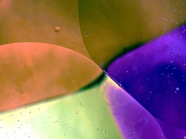 yüzen yağ damlaları farklı renklerde parıldıyor ve renkli bir arkaplanda hava kabarcıklarının yanında şekilleniyor.