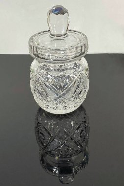 Aydınlatılmış kristal sürahi siyah camda duruyor, yansımayı görebilirsiniz, kristallerin üzerine saçılmış su damlalarını görebilirsiniz.