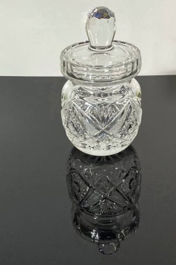 Aydınlatılmış kristal sürahi siyah camda duruyor, yansımayı görebilirsiniz, kristallerin üzerine saçılmış su damlalarını görebilirsiniz.