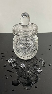 Aydınlatılmış kristal sürahi siyah camda duruyor, yansımayı görebilirsiniz, kristallerin üzerine saçılmış su damlalarını görebilirsiniz.