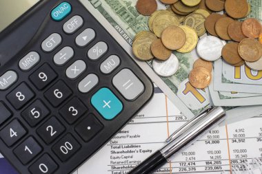 Finansal belgelerde dolar şeklinde banknotlar ve bozuk paralarla kopekler var. Belgeler üzerinde hesap makinesi ve kalem. Ticari mali konsept