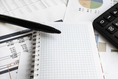 Finansal belgelerde hesap makinesinin yanında boş kareli bir defter var. İş ve Finans kavramı