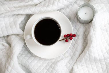 Beyaz ceketin üzerinde mum kenarında beyaz bir fincan kahve var. Rahatlama ve rahatlama kavramı.