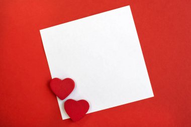 Kırmızı dokulu arka planda iki kırmızı kalbi olan beyaz bir çarşaf var. Metin için alanı olan tatil arkaplanı