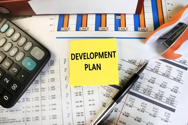 the development plan is written on a sheet that lies on the documents among the calculator red folder and pen. business concept