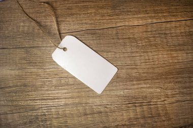 Ahşap desenli arka planda ipi olan beyaz bir etiket var. Mesaj için yer var. Konsept fotoğraf