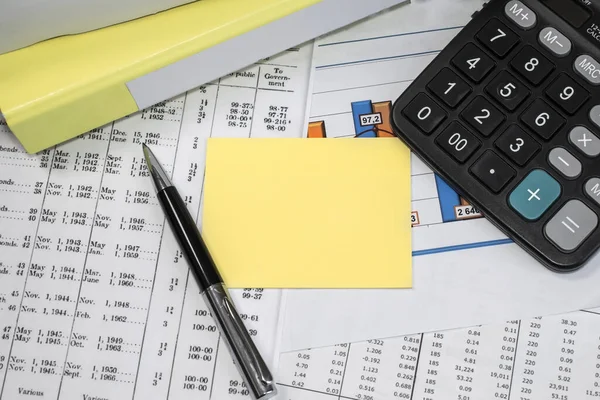 On the financial documents next to the calculator and the yellow folder there is a blank yellow sheet for records. Business and financial concept