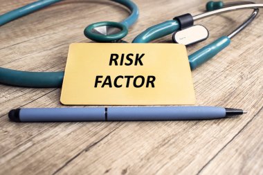 Risk faktörü, steteskopun yanında duran sarı etikete ve tahta bir masanın üzerindeki kaleme yazılmıştır..
