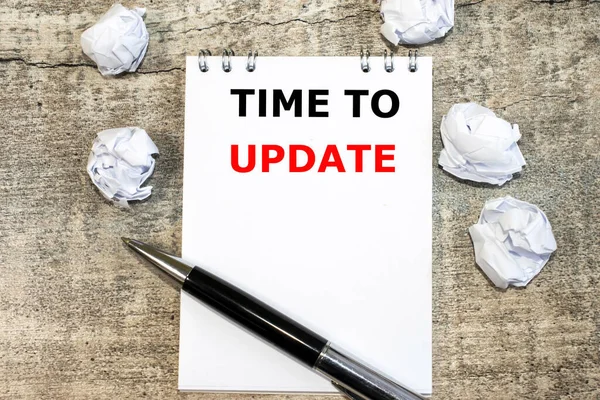 The update time is written on a notepad that lies on a wooden table near crumpled sheets of paper.