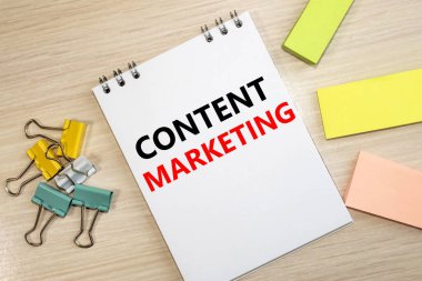 içerik pazarlaması, kırtasiyenin arasındaki ahşap bir masada duran bir deftere yazılmıştır..