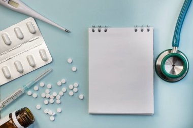 Stetoskop ve tıbbi malzemelerin yanında mesaj için yeri olan bir defter var. Tabletler ve bir termometre. Tıbbi konsept