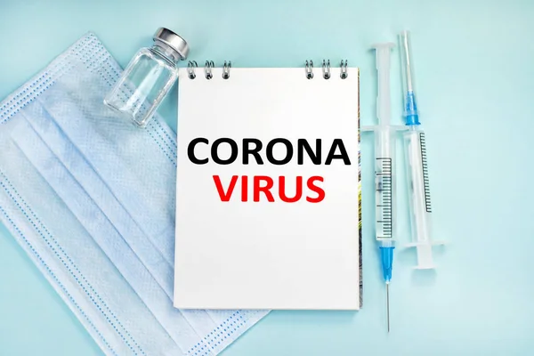 コロナウイルスという言葉は青い背景にあるメモ帳にあります 救急車と医療用フェイスマスクの注射器 医学的概念 — ストック写真