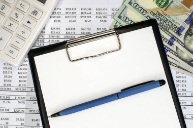 Mali belgesinde beyaz boş bir kağıt ve mavi bir kalem olan bir kırtasiye tableti. Beyaz hesap makinesi ve dolar. İş ve finansal konsept. İş Şablonu