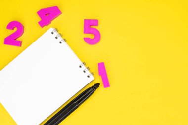 Sarı arkaplanda pembe numaralar arasında bir not defteri var. Metin için arkaplanda boşluk var. Eğitim kavramı