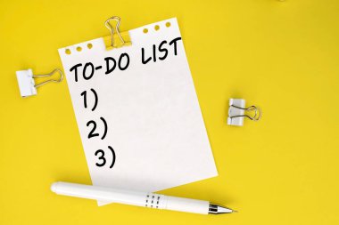 Beyaz bir kalemin yanında sarı bir arkaplanda görevlerin bir listesi yazılı beyaz bir sayfa vardır.