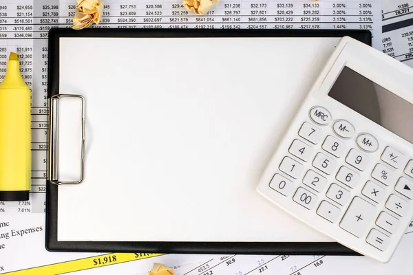 On the financial document next to a crumpled sheet of paper and a marker, there is a stationery tablet with space for text and a white calculator. Business and financial concept. Template