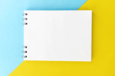 İki renkli geometrik arkaplanda boş bir defter var. Sarı ve mavi. Metin için alanı olan şablon