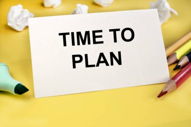 Renkli kalemler ve beyaz buruşuk kağıtlar arasında sarı bir zemin üzerinde duran beyaz bir sayfaya yazı yazmanın zamanı geldi..