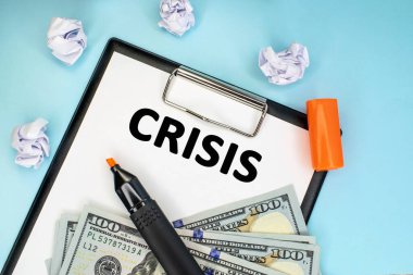 Kriz kelimesi buruşmuş kağıt ve dolarların yanında duran kırtasiye tabletine yazılmıştır. İş ve mali konsept