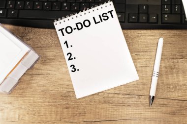 Kara klavyenin yanındaki ahşap bir masada yapılacak işler listesinin yazıldığı bir defter var. Eğitim ve iş konsepti