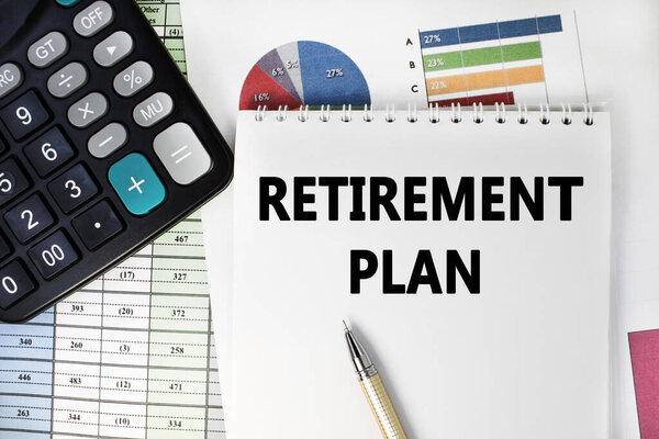 The retirement plan is written on a notebook that lies on a financial document near a black calculator.