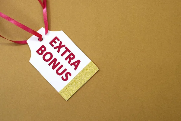 Extra bonus is written in red letters on a white tag for the price tag with a red ribbon. The concept of discounts and sales