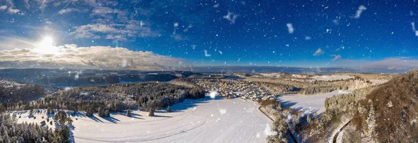 Prachtig winter wonderland uitzicht over een besneeuwd breed landschap bij de zwabische alb met sneeuwvlokken op de voorgrond van een blauwe zonnige hemel. — Stockfoto