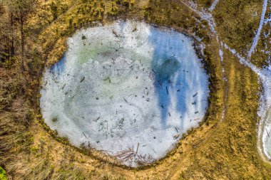 Donmuş bir gölün yuvarlak şekli, insansız hava aracından çekilen güzel bir kış manzarasına bakıyor..