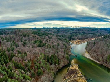 Isar nehri ile hava ormanı manzarası sonbahar ormanlarında bükülür ve arka planda Alp dağları bulunur..