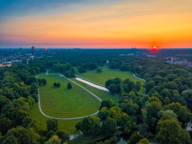 Yaz güneşinin doğuşuyla Münih Englischer Bahçesi 'nin muhteşem manzarası. Yeşil halka açık turistik mekan yukarıdan çekiliyor..