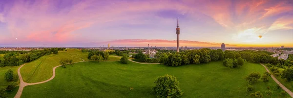 Lever de soleil rêveur sur le populaire parc olympique Munichs depuis une vue haute et panoramique avec un ciel matinal violet sur le hotspot idyllique touristique dans le centre de la capitale bavaroise. — Photo