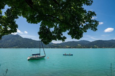 Turkuaz Tegernsee 'ye bir çift ve bir tekneyle bakın, arka planda Alp dağlarının güzel genişliğinde - fitness ve eğlence konsepti bir fotoğrafta.