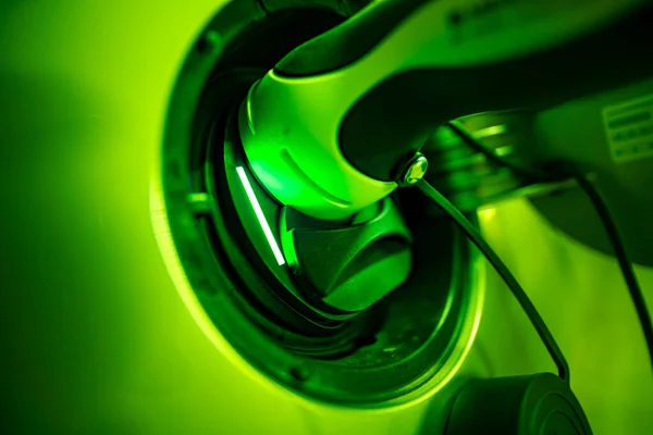 Charger plugged in an electric car - the green light shows the active charging process with ecological energy.