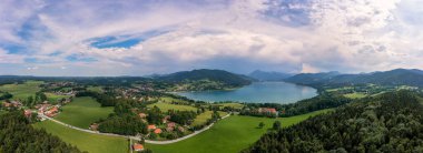 Tegernsee 'nin Bavyera dinlenme alanı, yüksek açılı Alpler manzarası güzel bir yaz gününde ön planda Gut Kaltenbrunn ile bir dron manzarası.