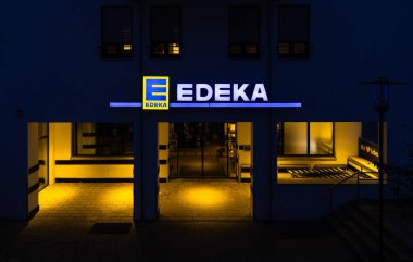 08041 Oberhaching, Hubertusstrasse 1 'deki edeka süpermarketi, 2021 yılında 19. ağustosta EDEKA logosu ve piyasa girişi ile 20.30' da mavi saatte yakıldı..
