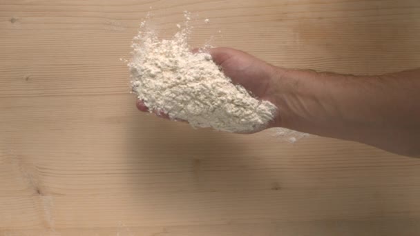 Мужская рука выливает муку на деревянную поверхность в замедленной обработке столешницы и выпечке — стоковое видео