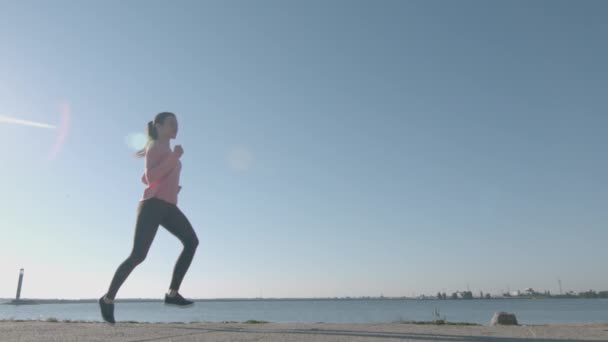 Donna che fa jogging e corre in super slow motion al fiume Flying Hair Wide Low Shot — Video Stock