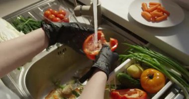 Çan biberini taze sebzeler ve ağır çekimde akan suyla lavaboda yıkamak.