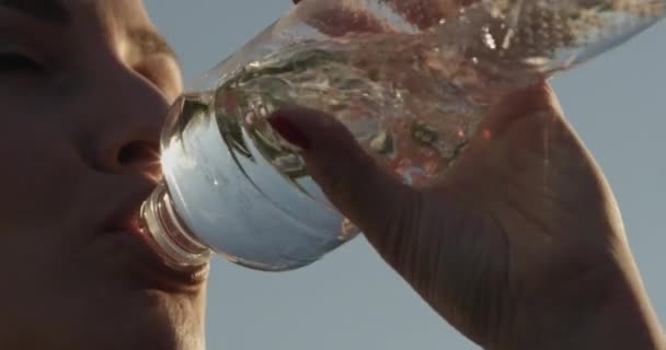 美丽女子在夕阳西下喝清澈瓶装水及背天的衣物 — 图库视频影像